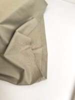 Tessuto beige morbido e lucido con pieghe eleganti su sfondo bianco.