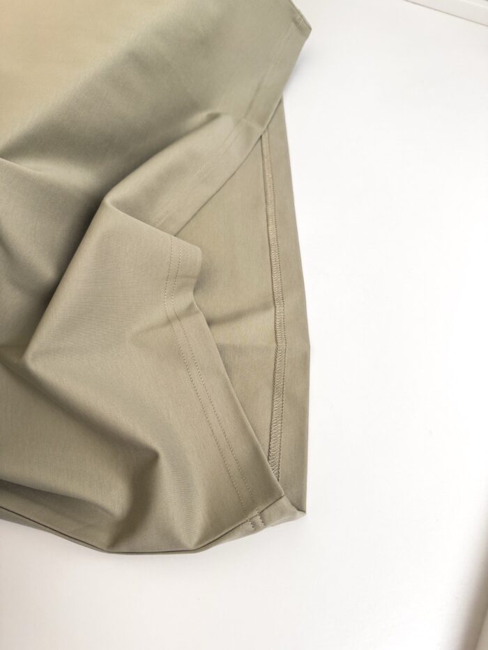 Tessuto beige morbido e lucido con pieghe eleganti su sfondo bianco.