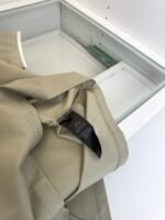 Pantaloni beige in cotone con etichetta di cura, pronti per il lavaggio.
