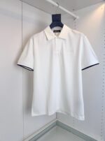 Maglietta polo bianca elegante con collo classico e dettagli a contrasto sulle maniche.