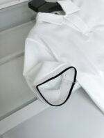 Maglietta polo bianca con bordo nero sui polsini, stile casual elegante e di alta qualità.