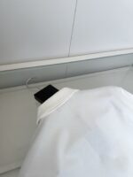 Camicia bianca elegante su espositore minimalista, tessuto di alta qualità e stile raffinato.