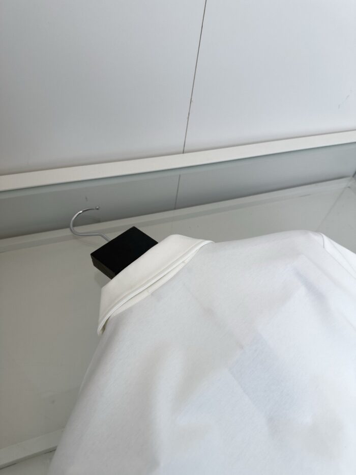 Camicia bianca elegante su espositore minimalista, tessuto di alta qualità e stile raffinato.
