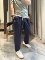 Look casual con t-shirt grigia, jogger blu e sneakers bianche in ambiente luminoso e accogliente.