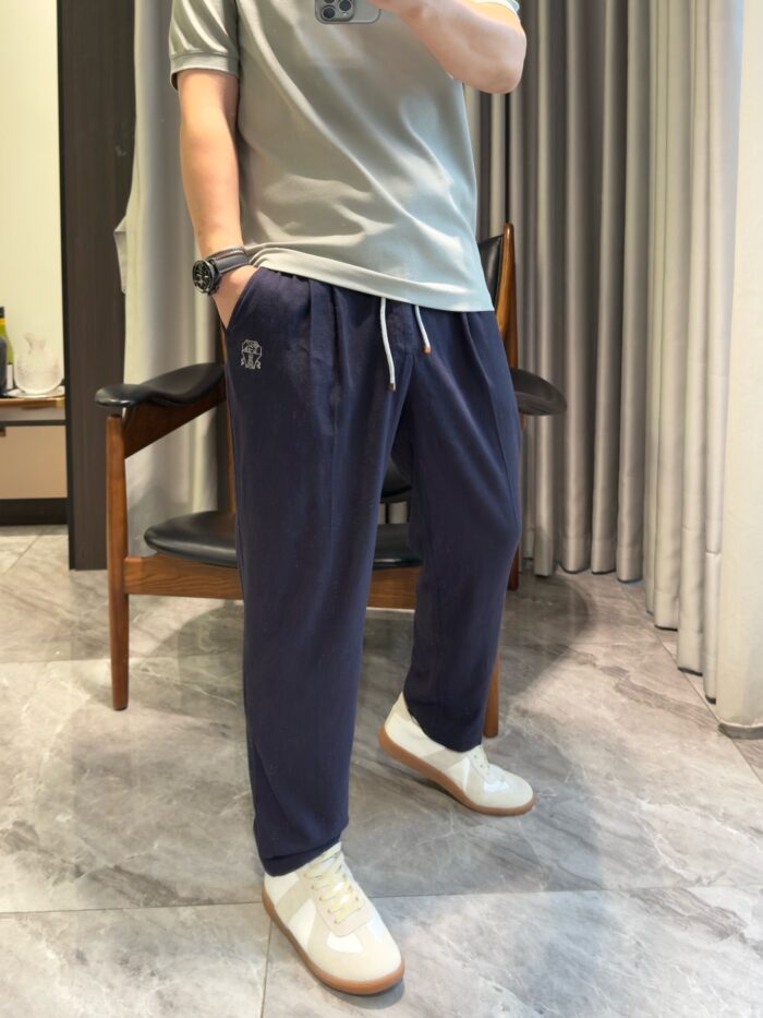 Look casual con t-shirt grigia, jogger blu e sneakers bianche in ambiente luminoso e accogliente.