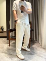 Uomo in look casual eleganza con polo bianca, pantaloni comodi e sneakers bianche sofisticate.