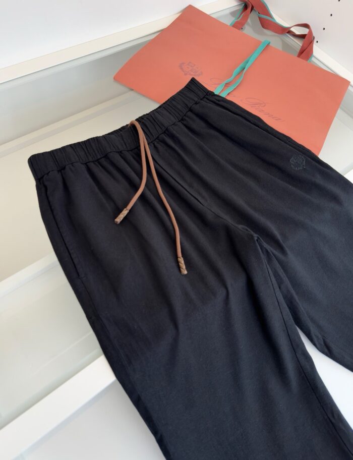 Pantaloni casual neri con cintura a cordino e borsa arancione moderna e versatile.