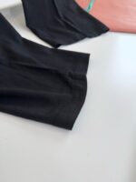 Tessuto nero elegante con dettaglio corallo, stile minimalista e pratico per ogni occasione.