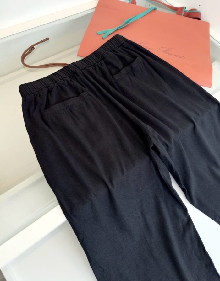 Pantaloni neri casual con borsa color pesca, stile elegante e comfort quotidiano.