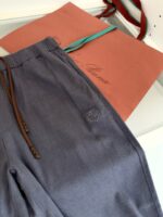 Pantaloni eleganti in tessuto morbido con dettaglio logo e borsa corallo raffinata.