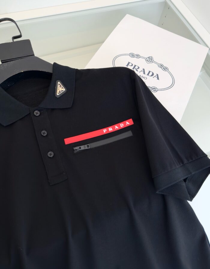 Maglietta polo Prada nera con logo rosso e dettagli moderni, stile elegante e di lusso.