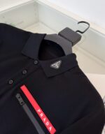 Maglietta polo Prada nera con logo triangolare e tasca con zip rossa elegante e moderna