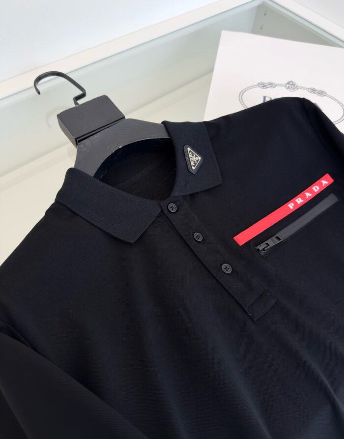 Maglietta polo nera elegante con logo triangolare e striscia rossa, perfetta per stile sofisticato.