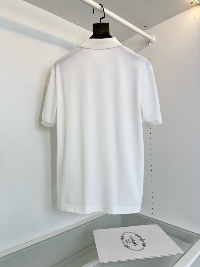 Maglietta polo bianca elegante su appendiabiti, stile minimalista e servizio curato.