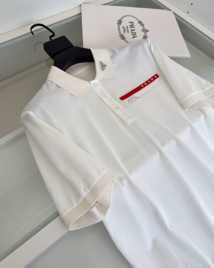 Maglietta polo bianca con dettaglio rosso, logo elegante e design moderno.