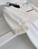 Maglietta polo bianca con colletto, risvolti e dettaglio con etichetta rossa.