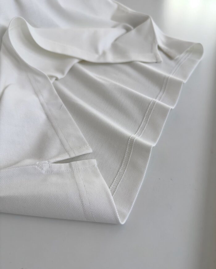 Camicia bianca elegante in cotone, piegata con attenzione ai dettagli e stile minimalista.