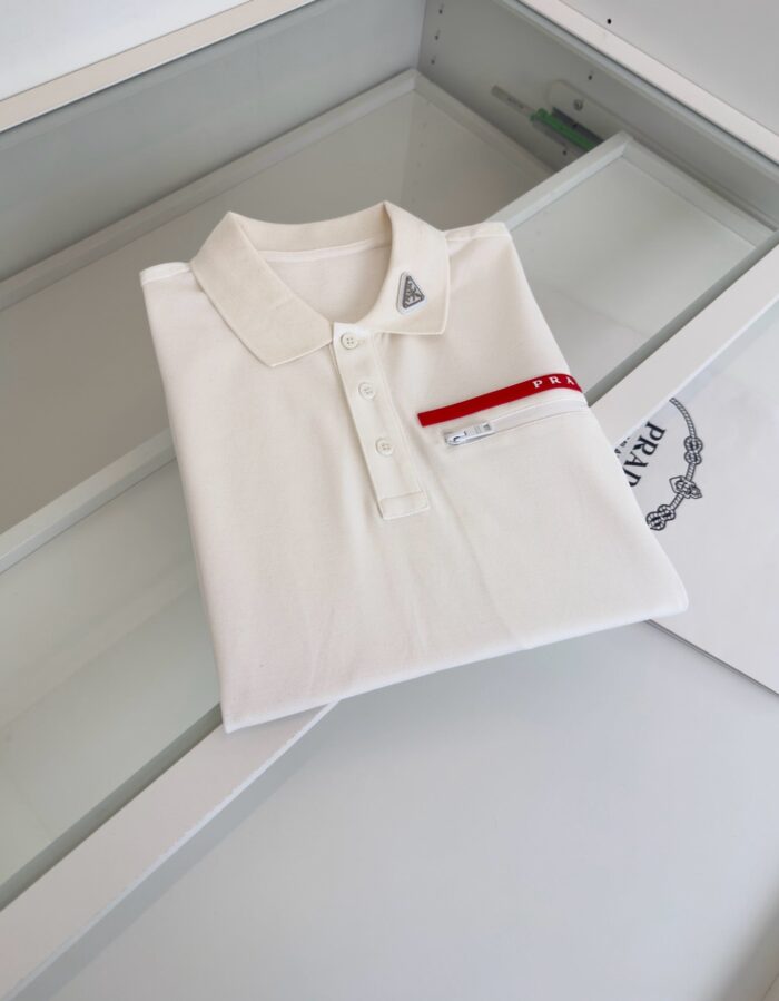 Maglietta polo bianca con dettaglio rosso, stile elegante e moderna su contenitore trasparente.