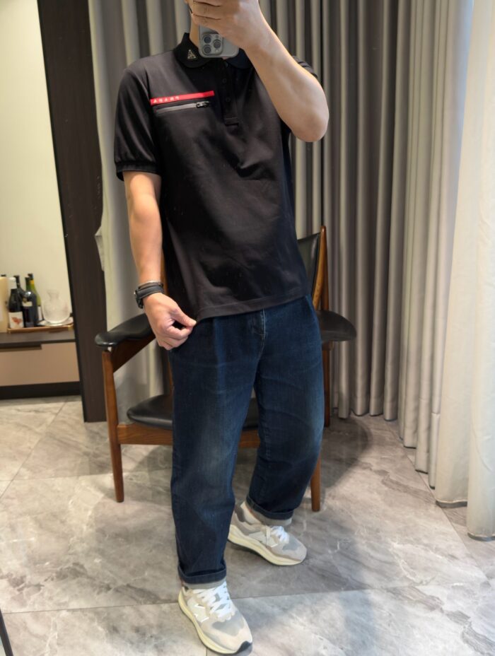 Uomo casual con polo, jeans e sneakers in un interno moderno e luminoso.