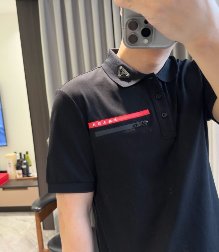 Persona con polo nera e striscia rossa in un ambiente domestico elegante.