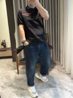 Abbigliamento casual con polo nero e jeans in ambiente moderno e luminoso.