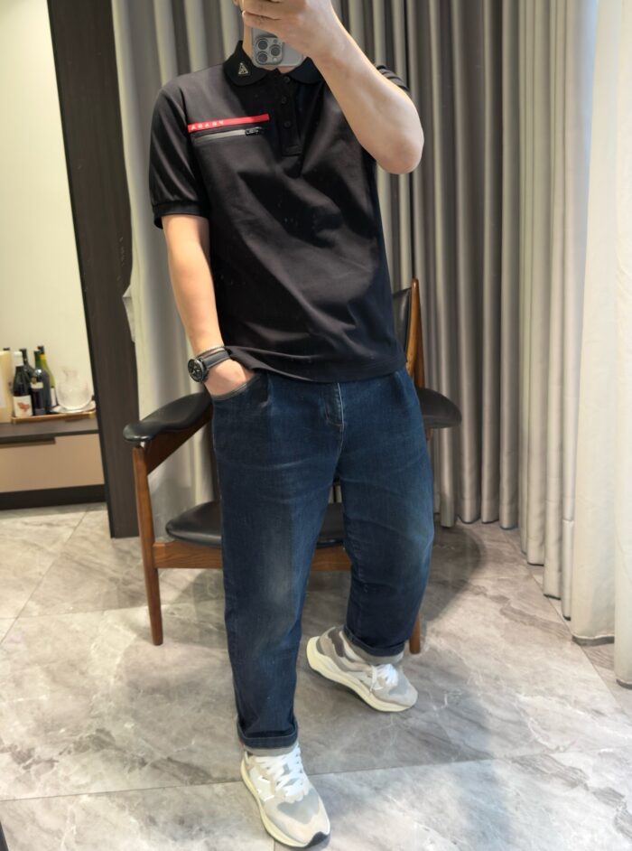 Abbigliamento casual con polo nero e jeans in ambiente moderno e luminoso.