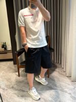 Persona in abbigliamento casual elegante con polo bianca e sneakers bianche, ambientazione raffinata.
