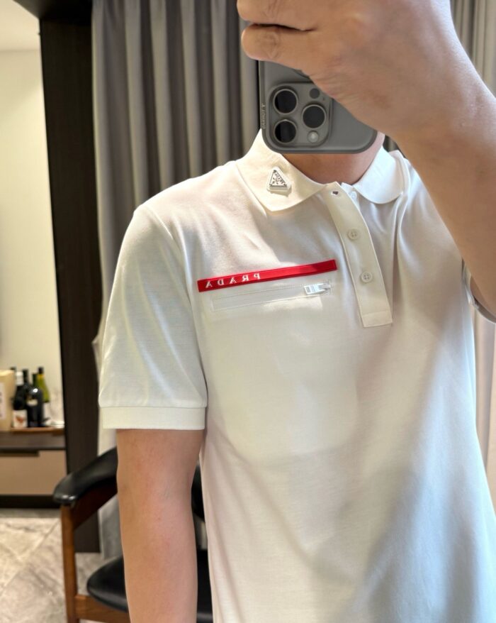 Selfie con maglietta polo bianca, striscia rossa e stile casual elegante.