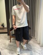 Stile casual in casa con polo, shorts cargo e sneakers bianche, ambiente rilassante e luminoso.