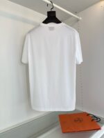 Maglietta bianca minimalista su gancio con borsa arancione in sfondo luminoso e moderno.