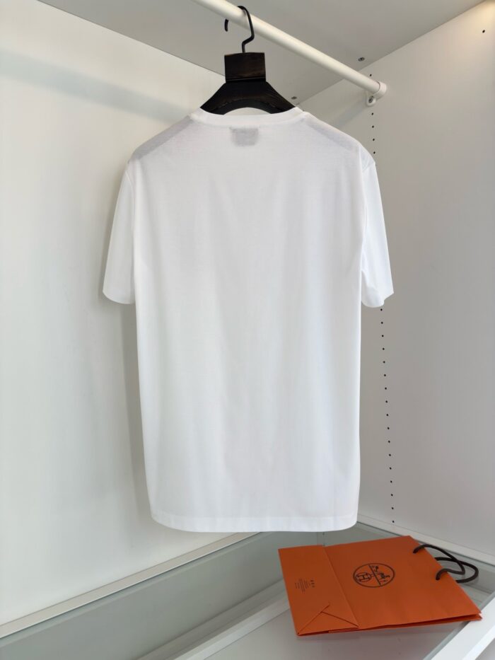 Maglietta bianca minimalista su gancio con borsa arancione in sfondo luminoso e moderno.