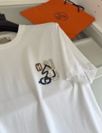 Maglietta bianca con grafica artistica, sfondo con borsa arancione e stile casual elegante.