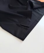 Tessuto nero sintetico elegante con pieghe e cuciture, ideale per moda e design moderni.