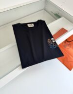Maglietta nera con logo colorato su sfondo minimalista e pulito, ideale per un look casual e moderno.