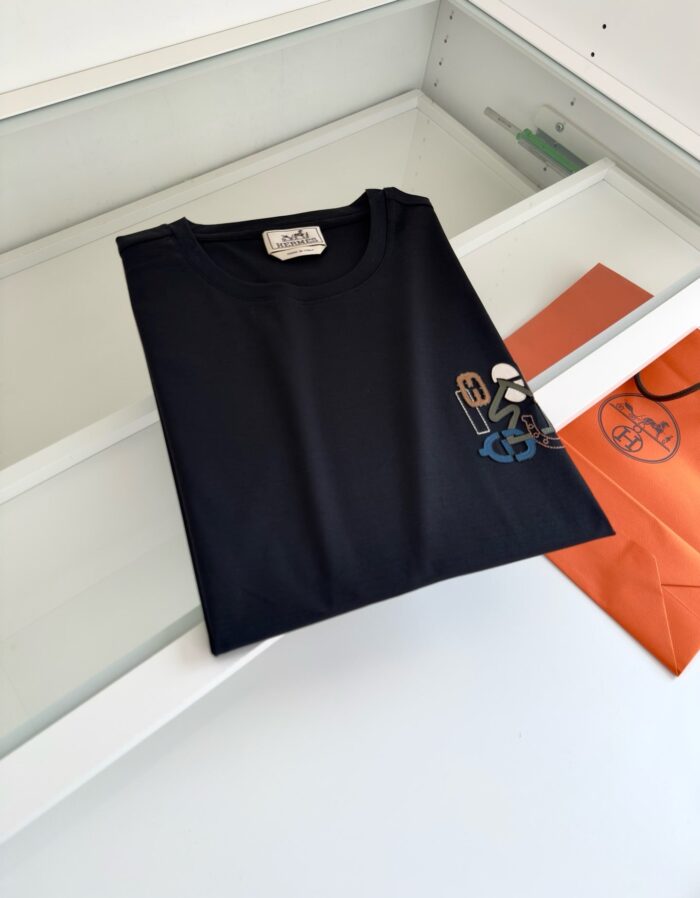 Maglietta nera con logo colorato su sfondo minimalista e pulito, ideale per un look casual e moderno.