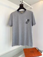 Maglietta grigia con grafica giocosa e borsa arancione, stile casual e trendy.