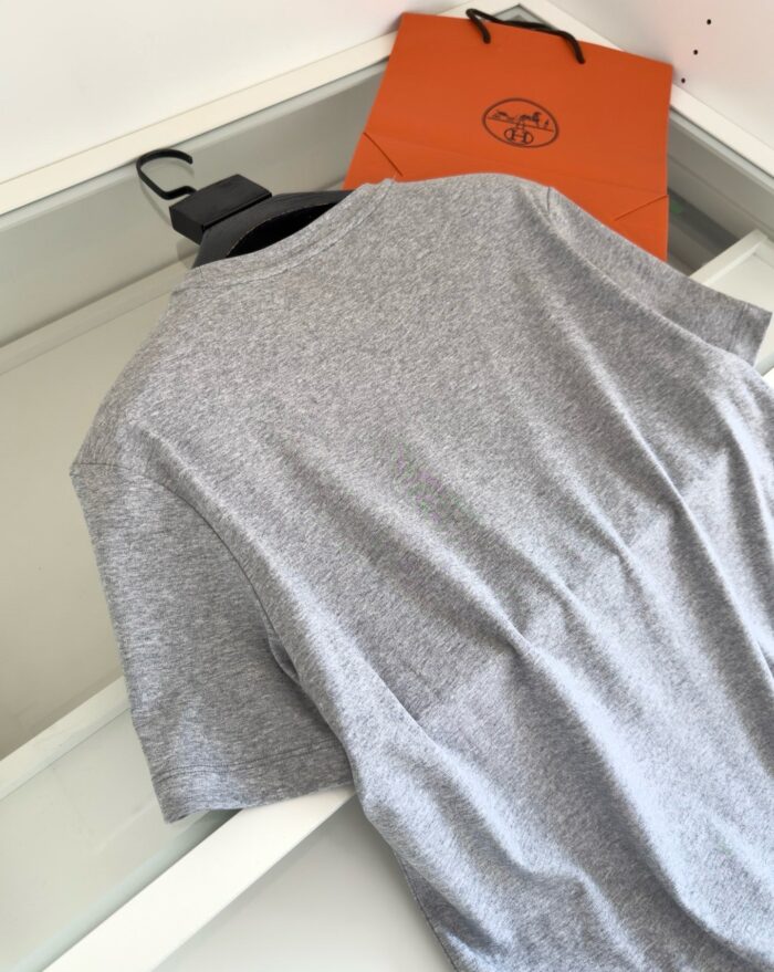 Maglietta grigia con borsa arancione, stile casual e pratico, perfetta per ogni occasione.