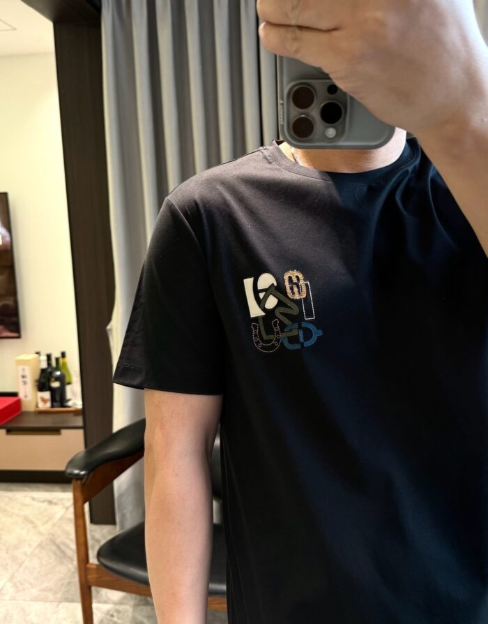 Selfie con T-shirt nera con logo colorato in soggiorno illuminato e moderno.