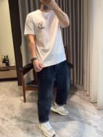 Persona con jeans e sneakers bianche in ambiente minimalista e moderno.