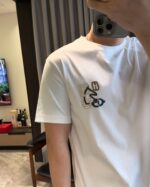 Selfie in casa con T-shirt bianca e design colorato, ambiente moderno e accogliente.