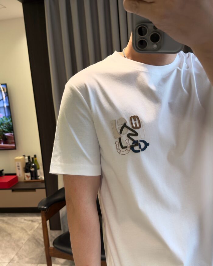 Selfie in casa con T-shirt bianca e design colorato, ambiente moderno e accogliente.