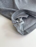 Maglietta grigia casual con manica arrotolata e cuciture visibili, ideale per look quotidiani.