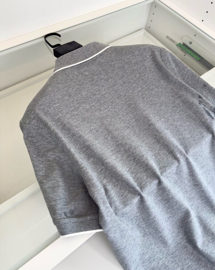 Maglietta polo grigia con colletto con piping bianco, stile semplice e moderno.