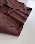Tessuto marrone morbido con orlo rifinito, drappeggio elegante e texture liscia, ideale per arredi.
