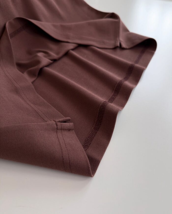 Tessuto marrone morbido con orlo rifinito, drappeggio elegante e texture liscia, ideale per arredi.