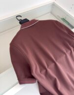 Maglietta polo bordeaux eleganti su appendiabiti, stile casual e raffinato in ambiente ordinato.