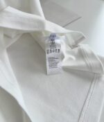 Maglietta bianca con etichetta di cura e taglia, semplice ed elegante.