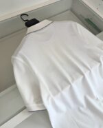 Maglietta polo bianca elegante su gruccia, stile casual e raffinato, pronta da indossare.