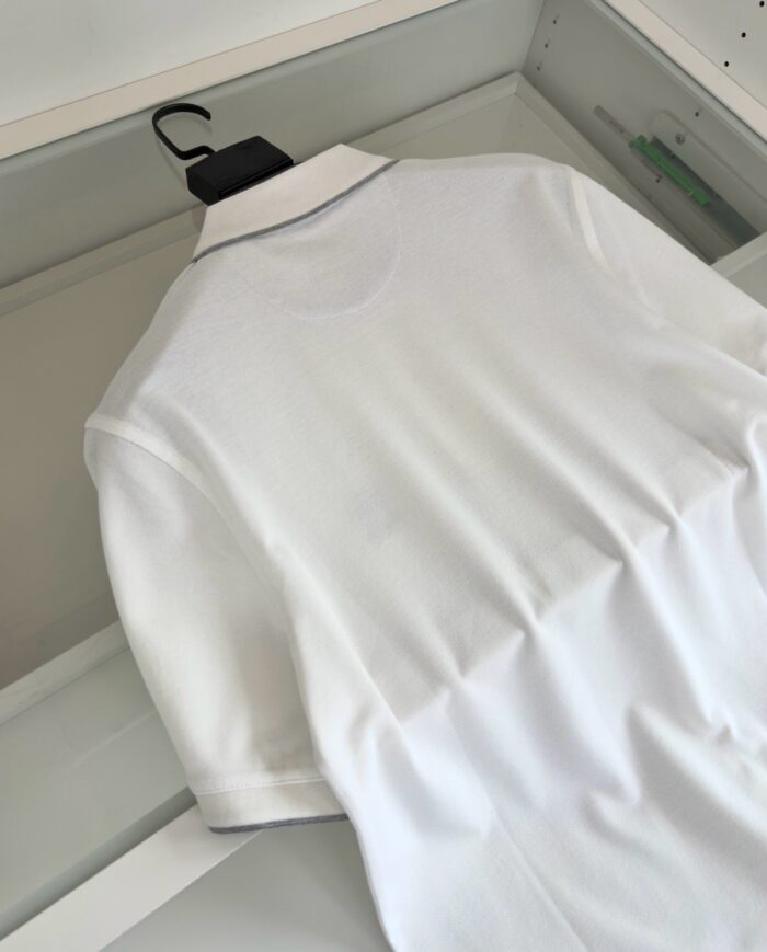 Maglietta polo bianca elegante su gruccia, stile casual e raffinato, pronta da indossare.