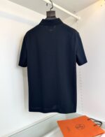Maglietta polo navy blu su gruccia con borsa arancione minimalista, stile casual elegante.